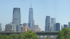Un horizonte urbano con rascacielos modernos, incluyendo una torre destacada con aguja.