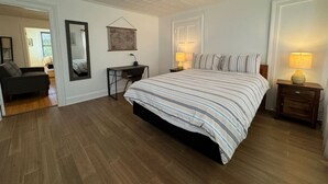 Un dormitorio con una cama grande, un escritorio y dos lámparas de noche.