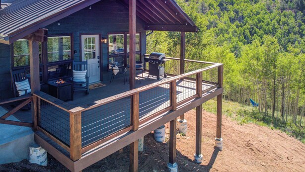 Eine Holzhütte mit Balkon, Grill und Feuerstelle.