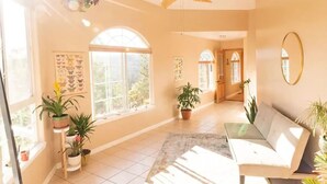 A spacious room with a large window, a ceiling fan, and a sofa. - Magical Mountaintop Oasis, Private 5-acre Retreat with Stunning Views! (Grass Valley)