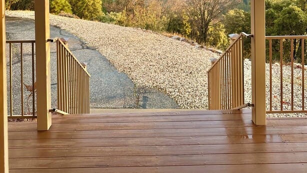 Een overdekt houten terras met uitzicht op een bebost dal.