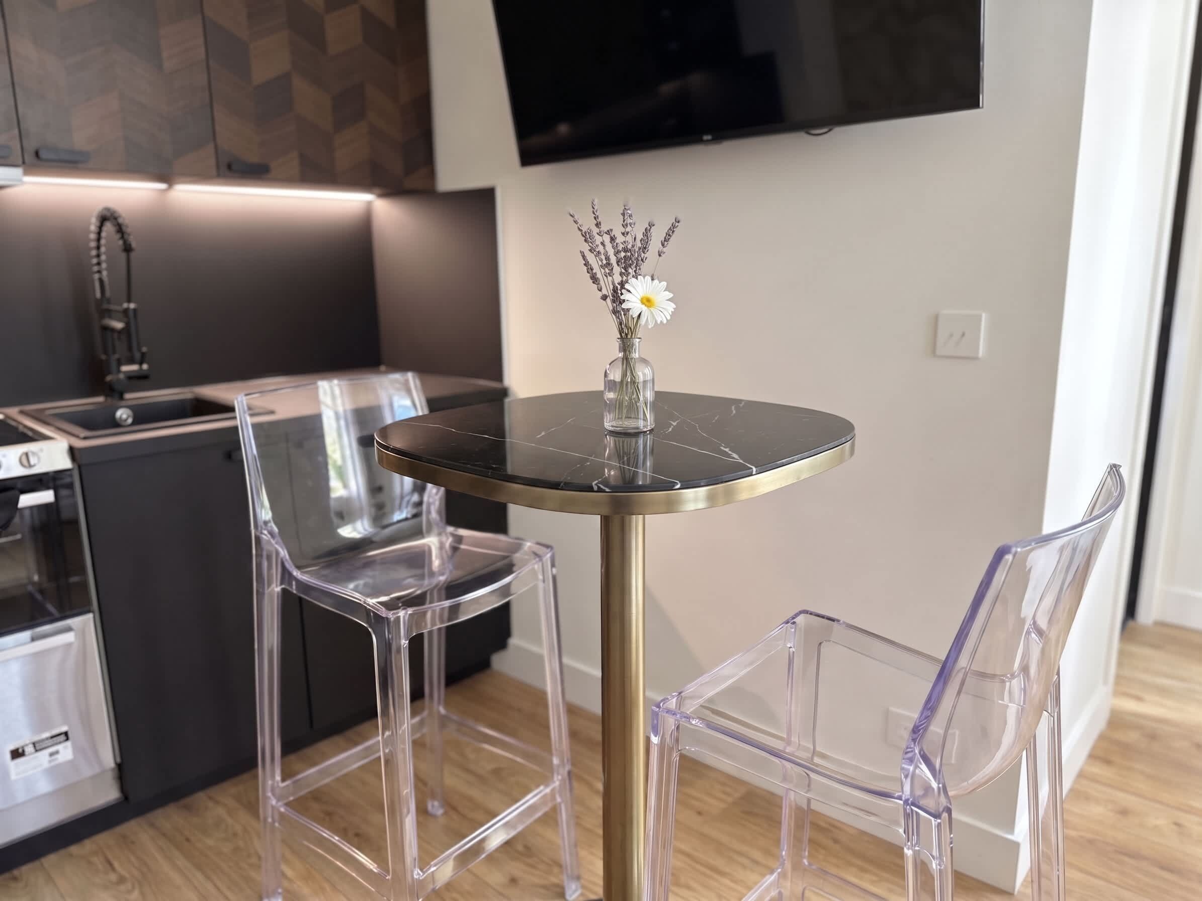 Una cucina moderna con zona pranzo, un tavolo rotondo e due sedie trasparenti.
