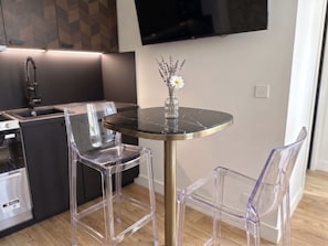 A modern kitchen with a dining area featuring a round table and two transparent chairs.
