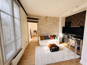 A modern living room with a sofa, a coffee table, and a kitchen area with a microwave and stove.