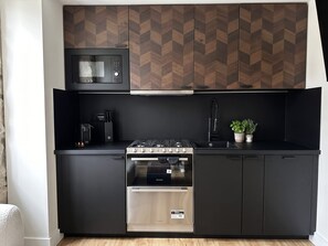 A compact kitchen with a microwave, gas stove, oven, and a small sink.
