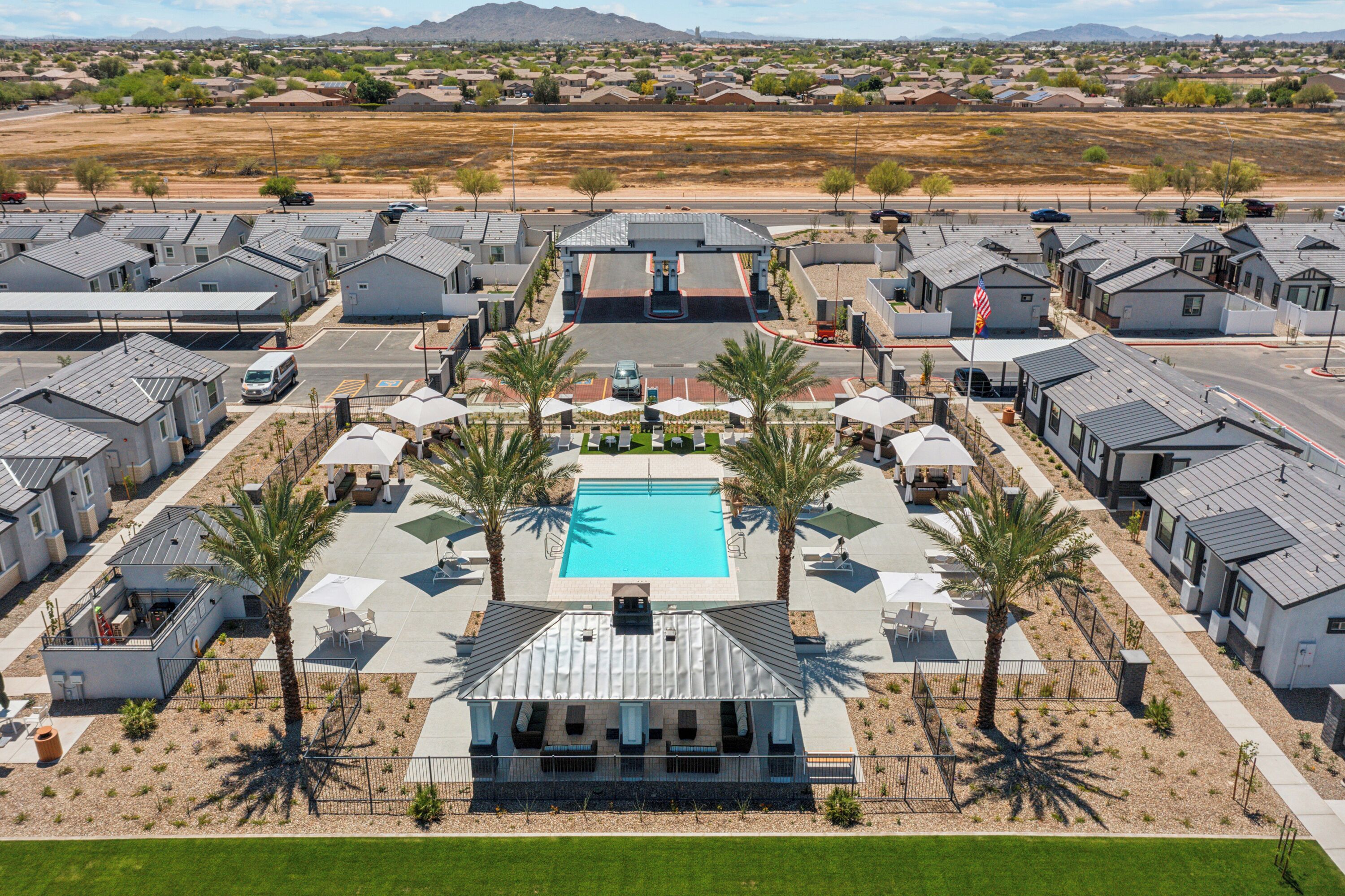 A residential area with modern houses, a central swimming pool, and palm trees.