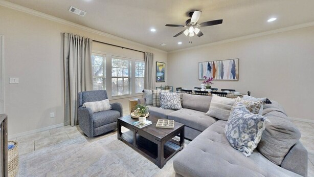 A living room with a grey sofa, a grey armchair, a coffee table, and a ceiling fan. - Uptown Aggie– 4BR Near Kyle Field (College Station)