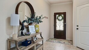 A wooden console table with a mirror, a lamp, and decorative items including a vase and a sign. - Uptown Aggie– 4BR Near Kyle Field (College Station)