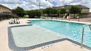 A swimming pool with a hot tub, surrounded by a fence, and a sign indicating a 6-inch depth. - Uptown Aggie– 4BR Near Kyle Field (College Station)