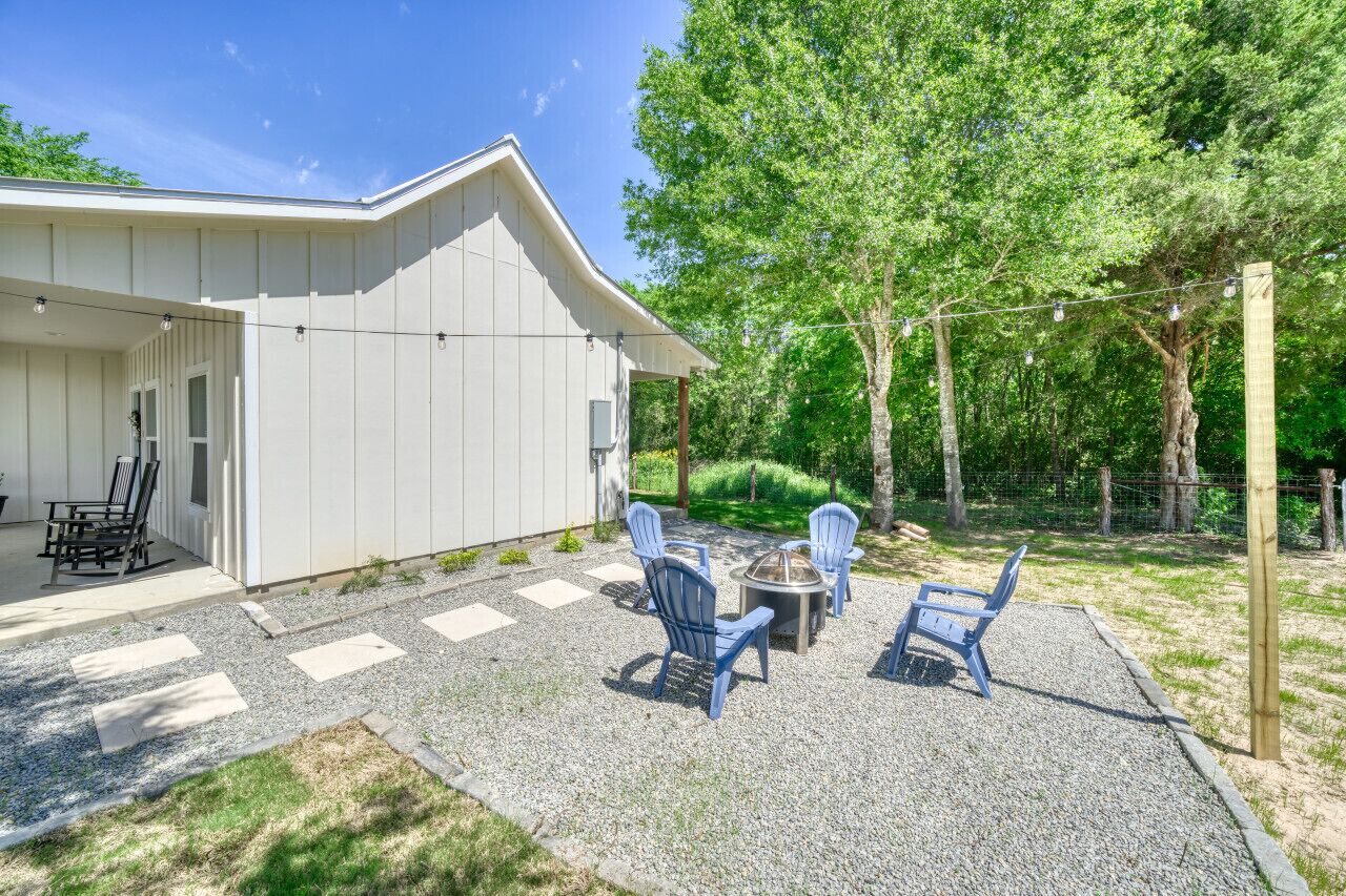 Ein Haus mit überdachter Terrasse, Sitzgelegenheiten im Freien und einem Kiesweg.