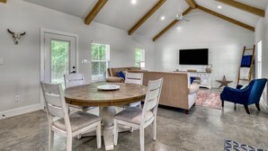 Una habitación amplia con techo alto, una mesa de comedor con sillas, un sofá, un televisor y una decoración con estrellas en la pared.