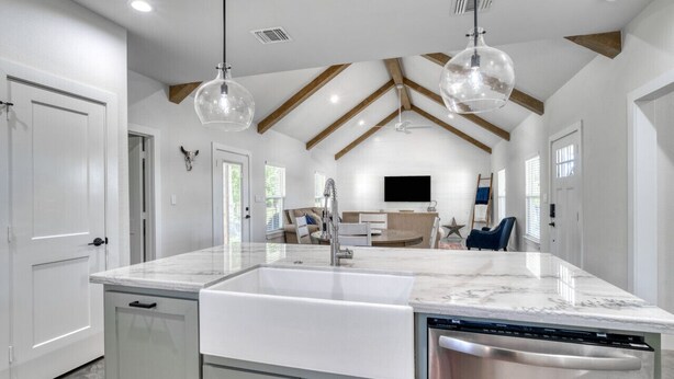 Una cocina amplia con una isla grande, muebles blancos y lavavajillas.