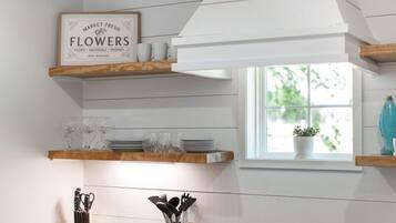 Een keuken met houten planken waarop keukengerei staat en een bord met verse bloemen.