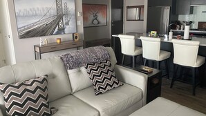 A modern living room with a sofa, a coffee table, and a dining area with chairs and a table. - Luxury 2 bedroom,  2 bath condo in the beautiful west end of downtown Calgary.  (Calgary)