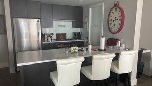 A modern kitchen with a stainless steel refrigerator, a gas stove, and a large island with bar stools. - Luxury 2 bedroom,  2 bath condo in the beautiful west end of downtown Calgary.  (Calgary)