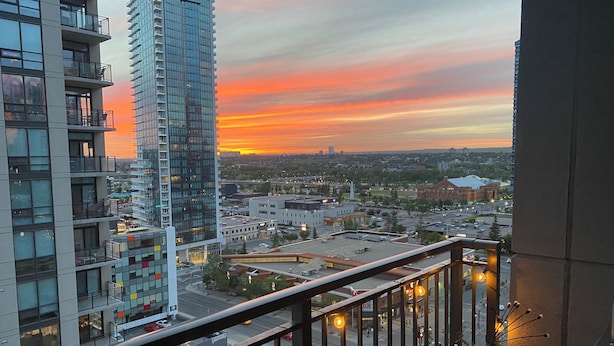 A high-rise building with a sunset view, a balcony with railings, and a cityscape in the background. - Luxury 2 bedroom,  2 bath condo in the beautiful west end of downtown Calgary.  (Calgary)
