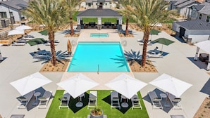 A pool area with lounge chairs and umbrellas, surrounded by palm trees and modern houses. - Gleaming Contemporary Home Pool  BBQ (Buckeye)