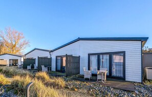 A row of modern, single-story mobile homes with large windows and a wooden deck. - Apartments Boddenblick (Sagard)
