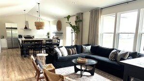 Ein modernes Wohnzimmer mit einer Eckcouch, einem Essbereich und einer Küche im Hintergrund.
