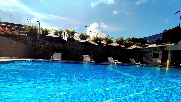 A clear blue swimming pool with lounge chairs and a stone wall. - CASA DE PIEDRA (Melgar)
