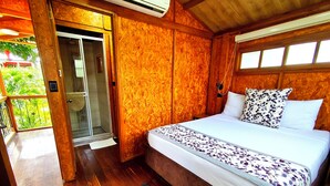 A wooden room with a bed, a door leading to a balcony, and a shower area. - CASA DE PIEDRA (Melgar)
