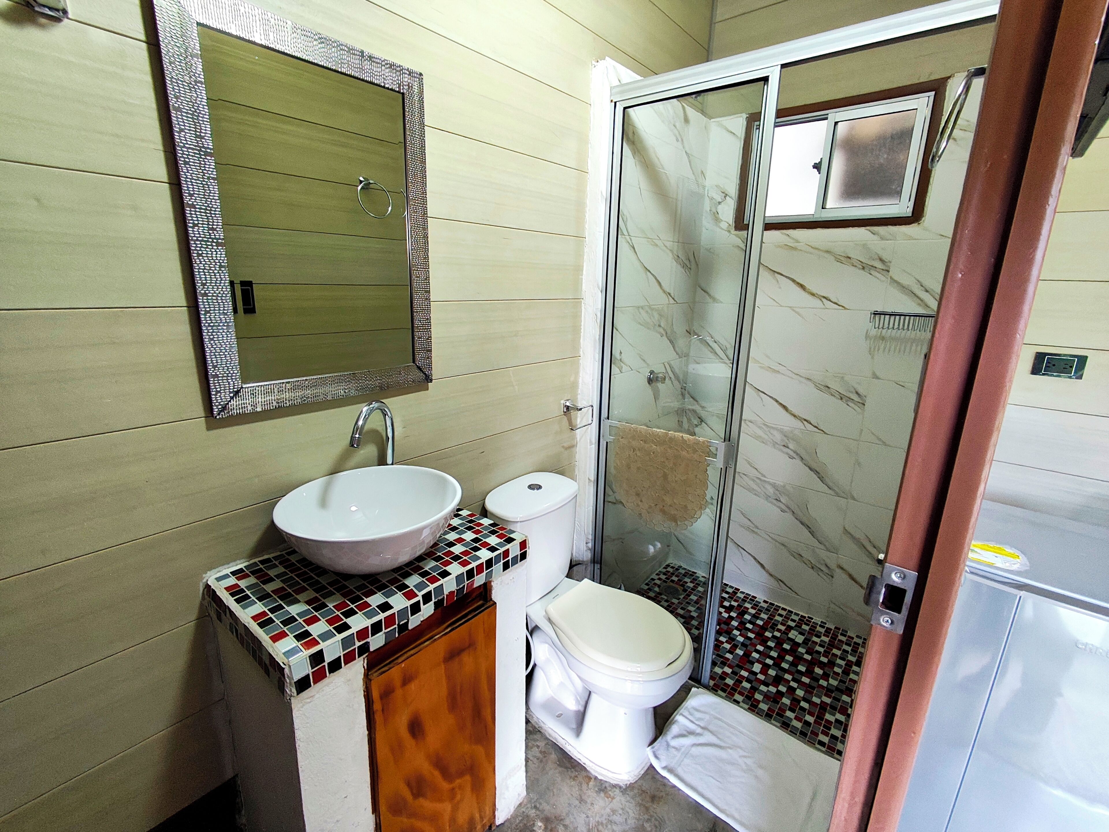 Un baño con lavabo, inodoro y cabina de ducha de vidrio.