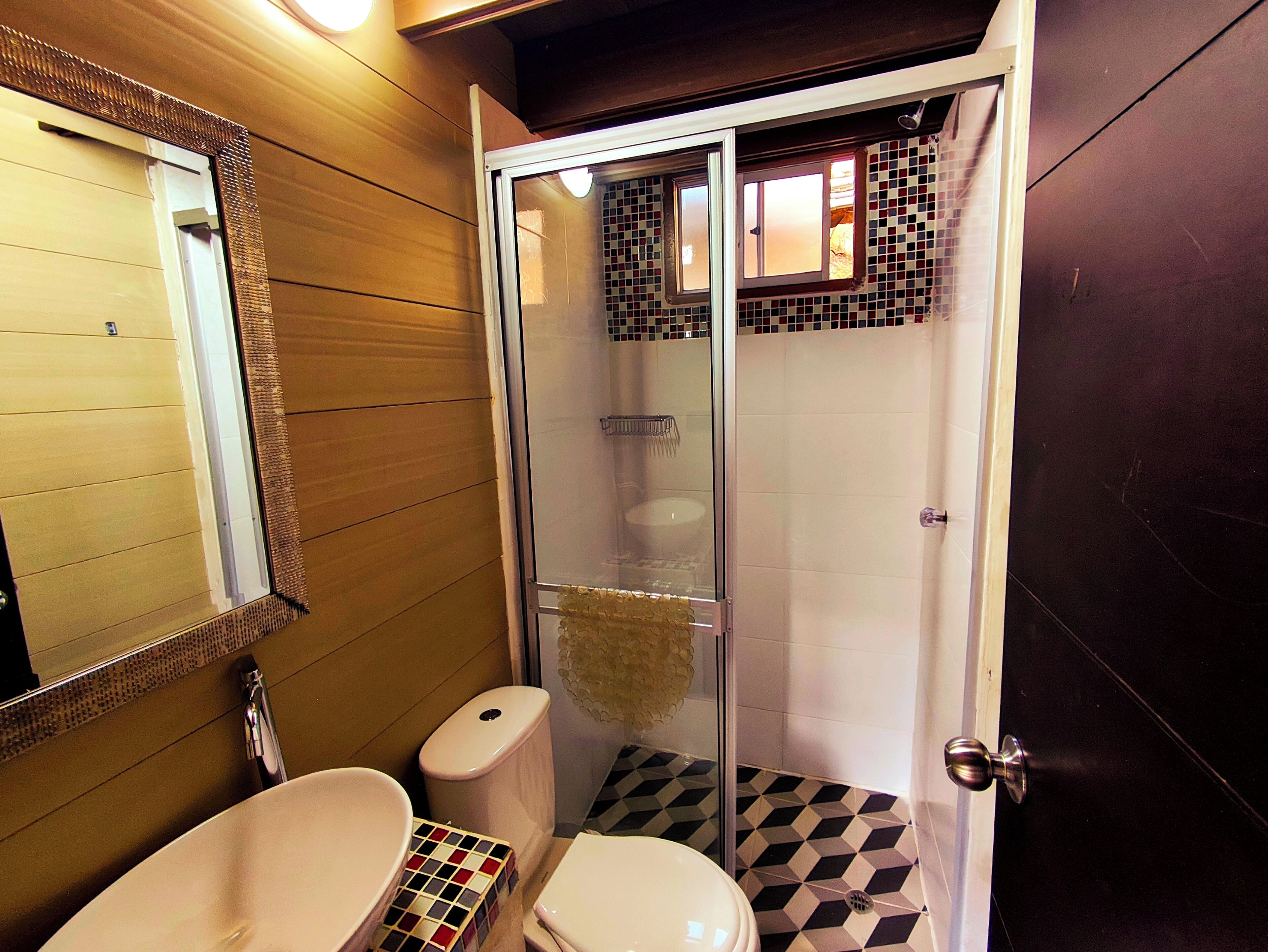A bathroom with a glass-enclosed shower, a white toilet, and a sink.