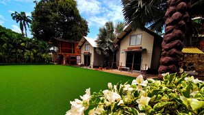 A house with a green lawn, white flowers, and a stone wall. - CASA DE PIEDRA (Melgar)
