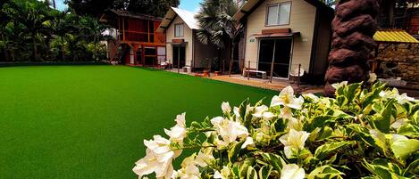 A house with a green lawn, white flowers, and a stone wall.