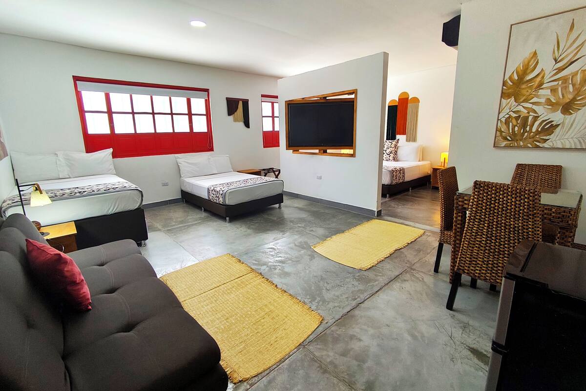 Ein modernes Wohnzimmer mit Sofa, Bett, Fernseher und Essbereich.