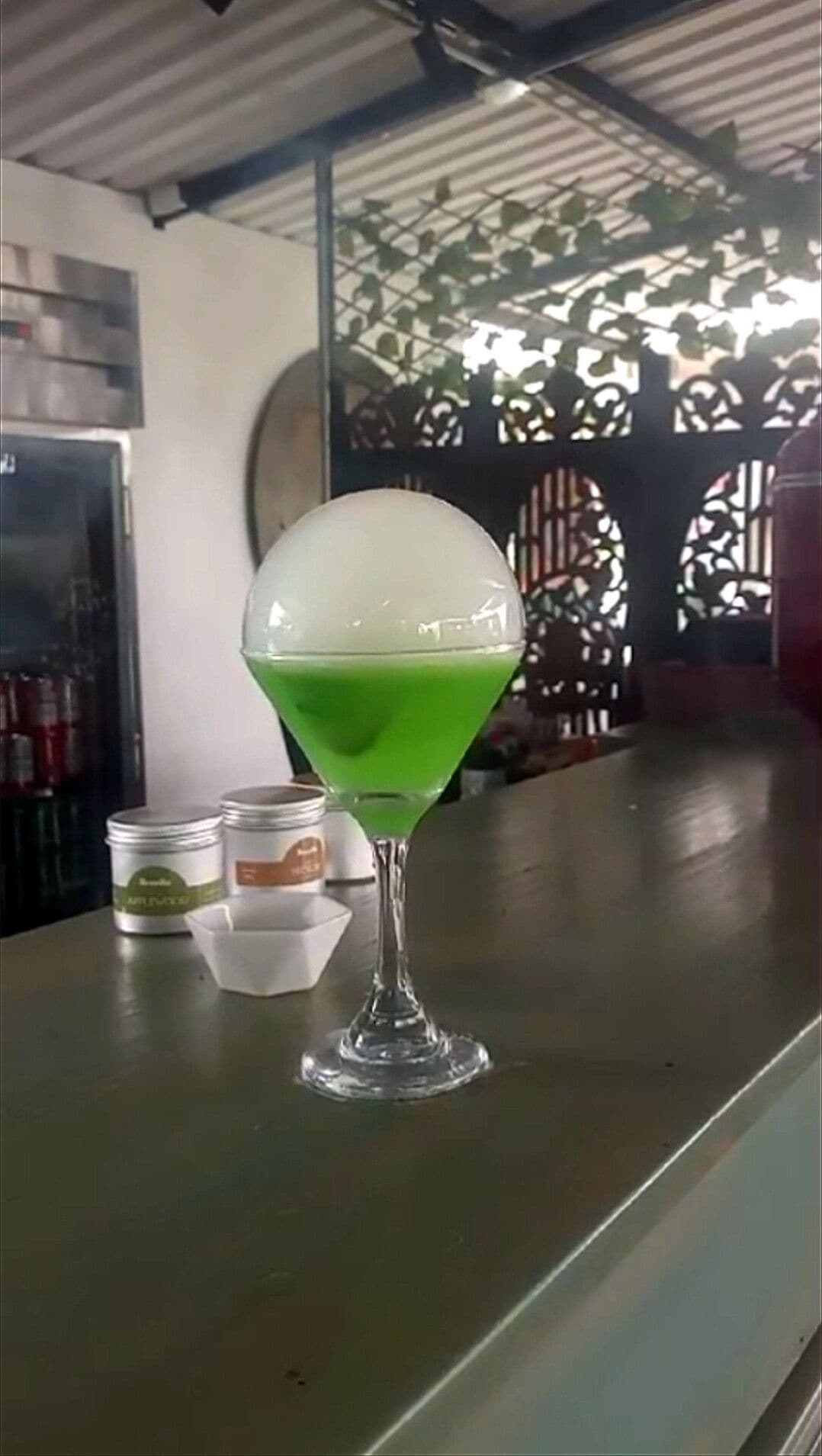 Una copa de martini con líquido verde sobre una barra.