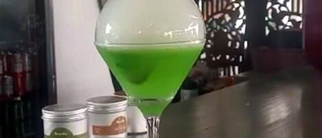 Una copa de martini con líquido verde sobre una barra.