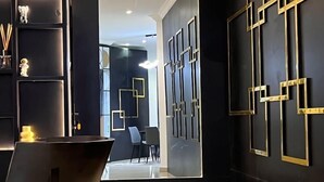 Een modern interieur met een donkere muur, geometrische gouden frames en een spiegelende vloer.