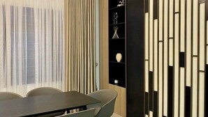 Een moderne eetruimte met een donker houten tafel en stoelen, een witte airconditioning en een decoratieve wand met verticale panelen.