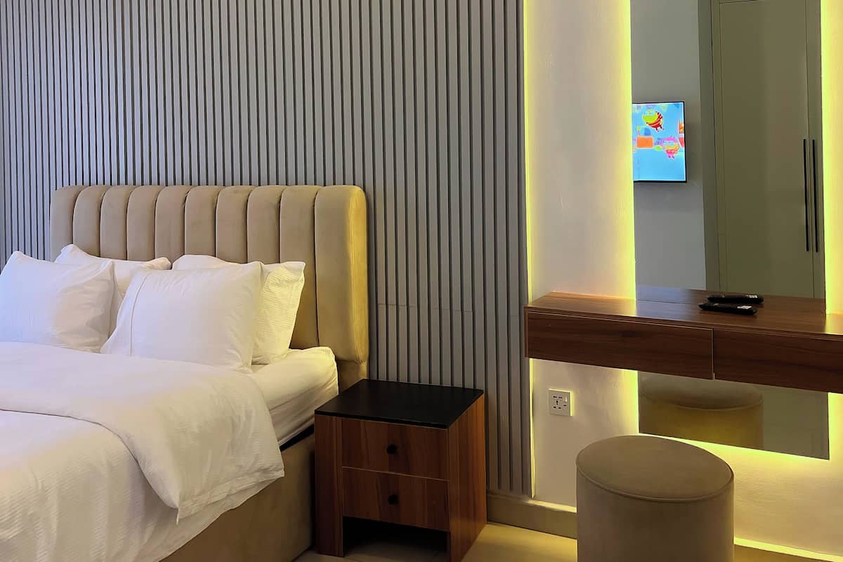 Une chambre à coucher moderne avec un lit, une table de chevet et un petit tabouret.