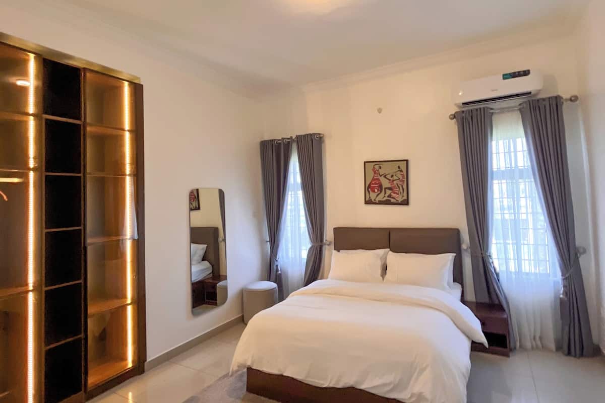 Une chambre moderne avec un grand lit, une armoire et un appareil de climatisation.