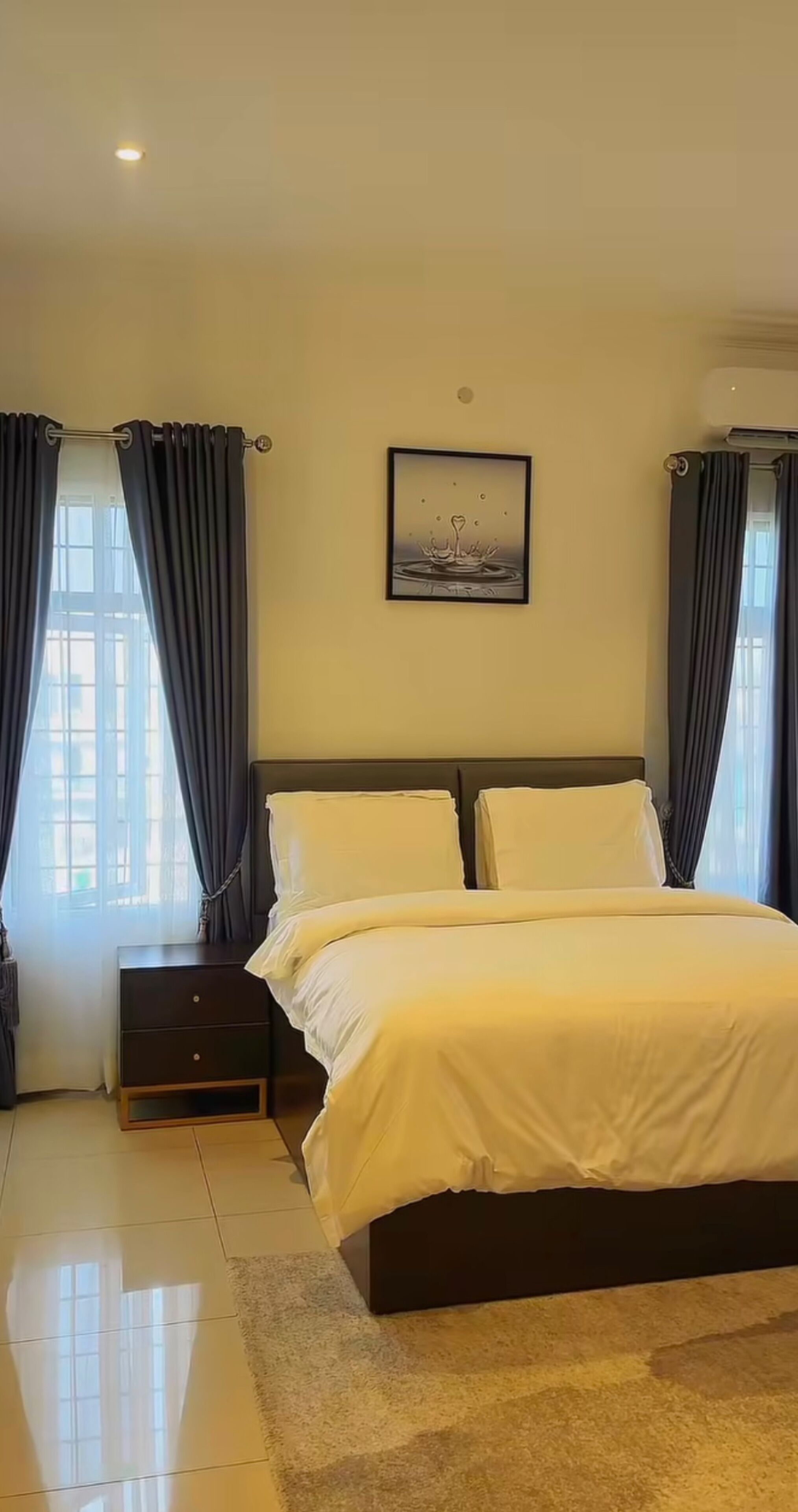 Une chambre à coucher bien rangée, avec un lit, des tables de chevet et un tableau accroché au mur.