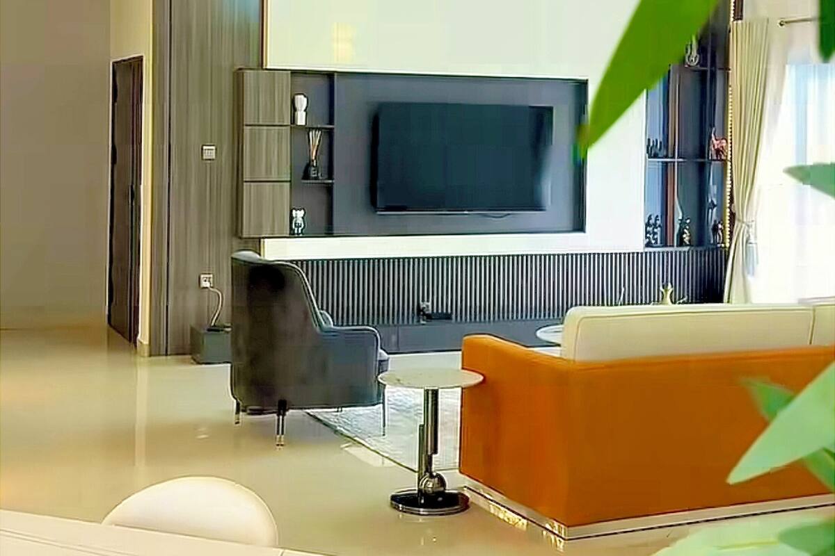 Un salon moderne avec un téléviseur à écran plat fixé au mur, un canapé blanc et une table à manger avec des chaises.