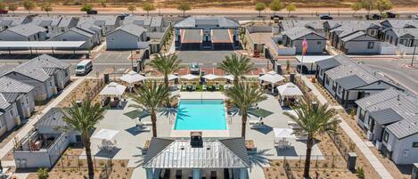 A residential area with modern houses, a central swimming pool, and palm trees.