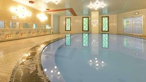 Una piscina interior con suelo de baldosas, pared de ladrillo e iluminación empotrada en el techo.
