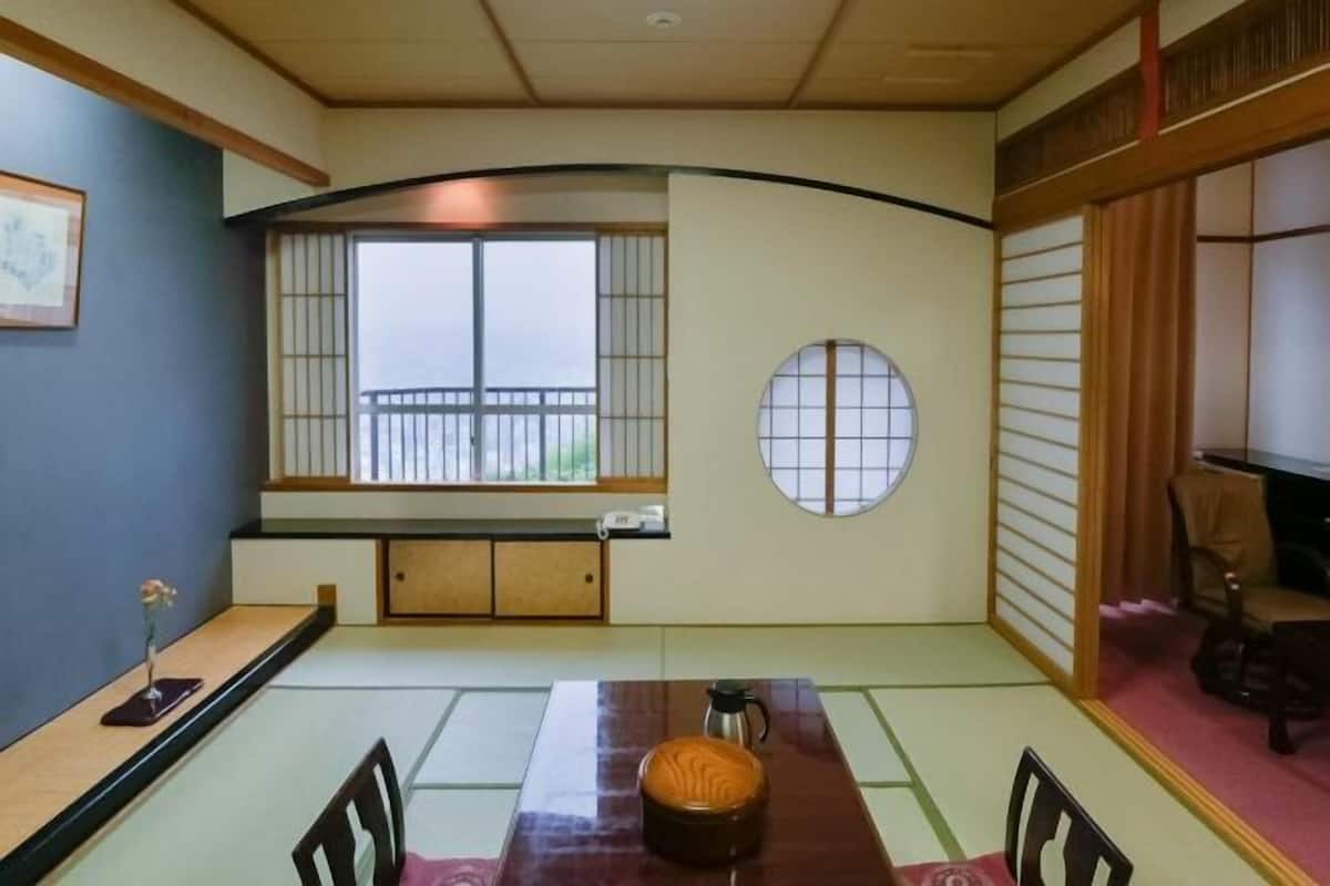 A traditional Japanese room with tatami flooring, a low table, a round window, and sliding doors.