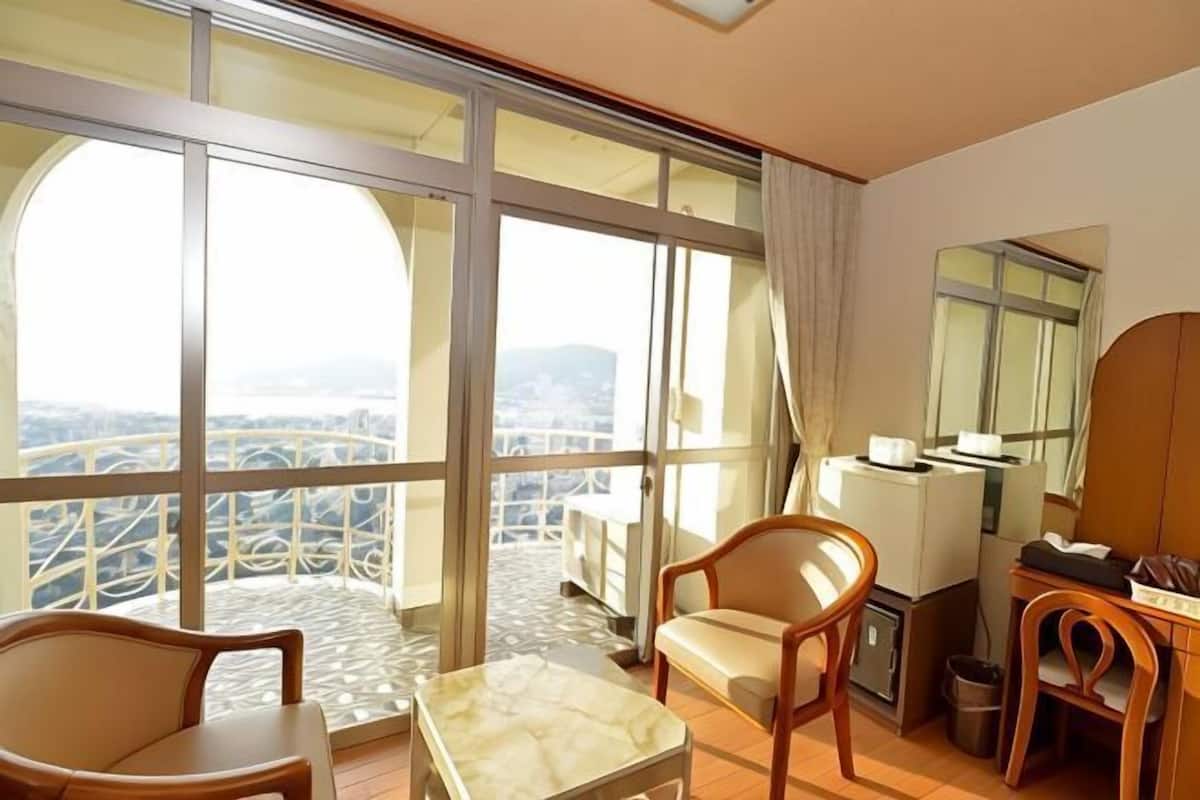 Une chambre d’hôtel dotée d’un grand balcon, d’un coin repas avec une table et des chaises, et offrant une vue sur le paysage urbain.