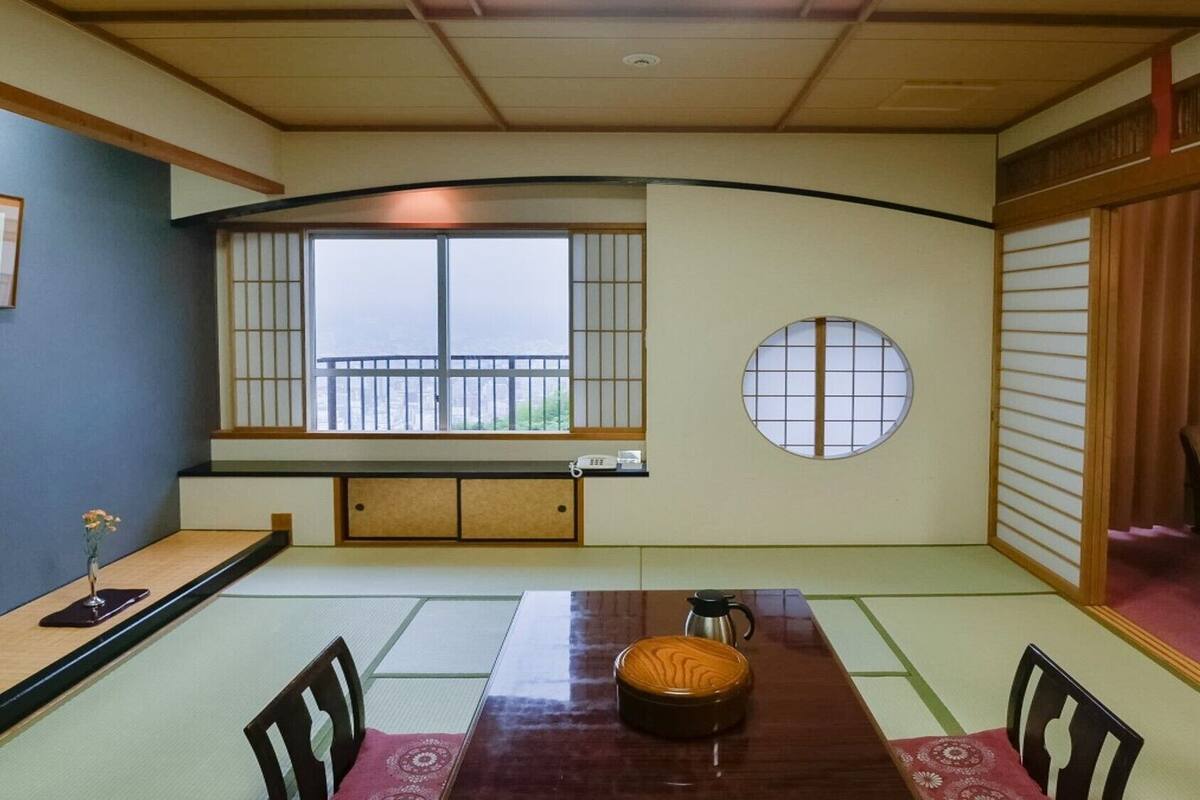 A traditional Japanese tatami room with a tatami mat floor, a low table with a tea set, and sliding doors.