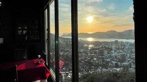 Una habitación con un ventanal grande que da a un paisaje urbano al atardecer.