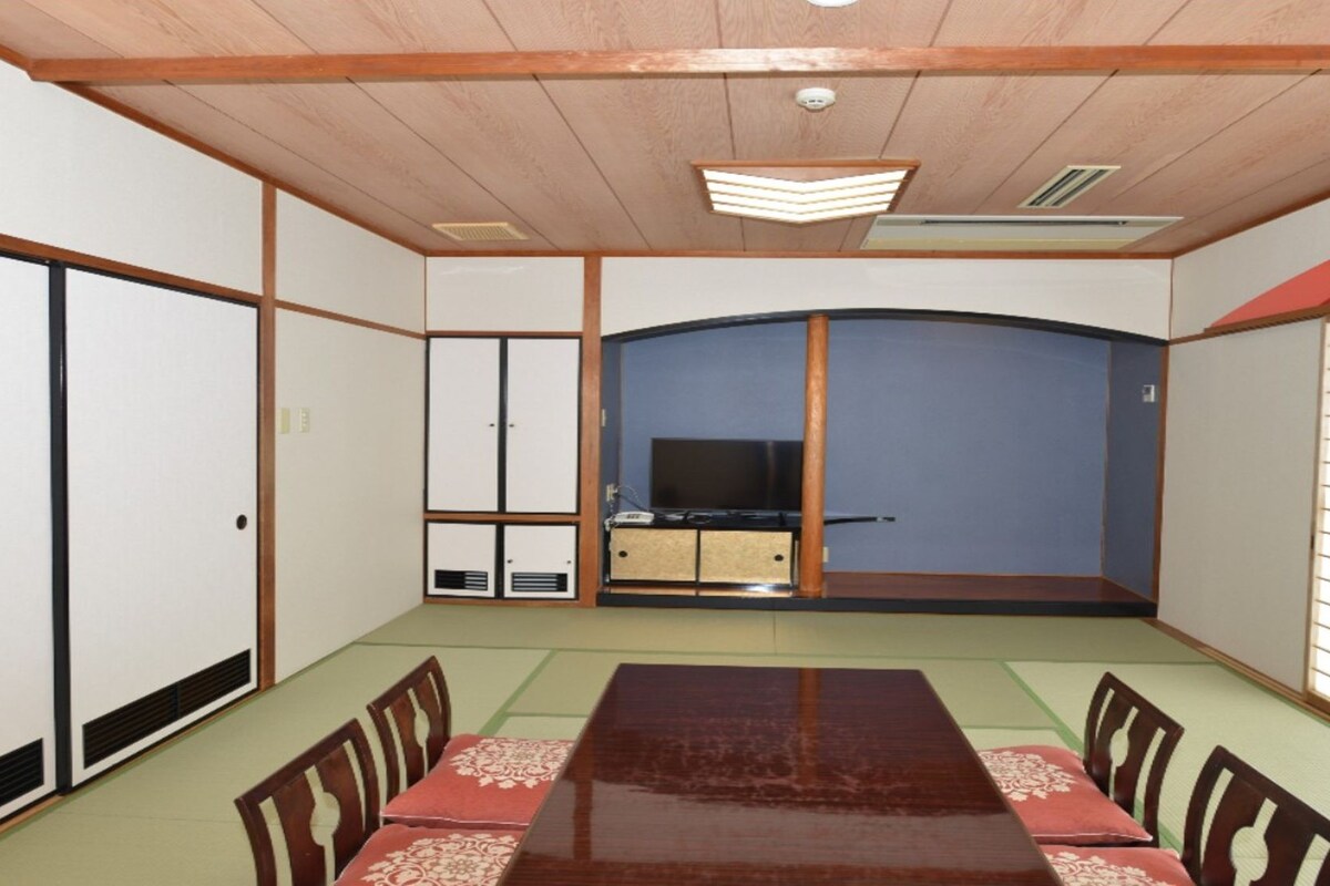 Una habitación tradicional japonesa con suelo de tatami, una mesa baja y puertas correderas.