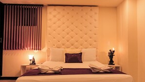A hotel room with a large bed, a headboard, a nightstand, a lamp, and a statue. - Hotel Plaza Garibaldi (Caldas)