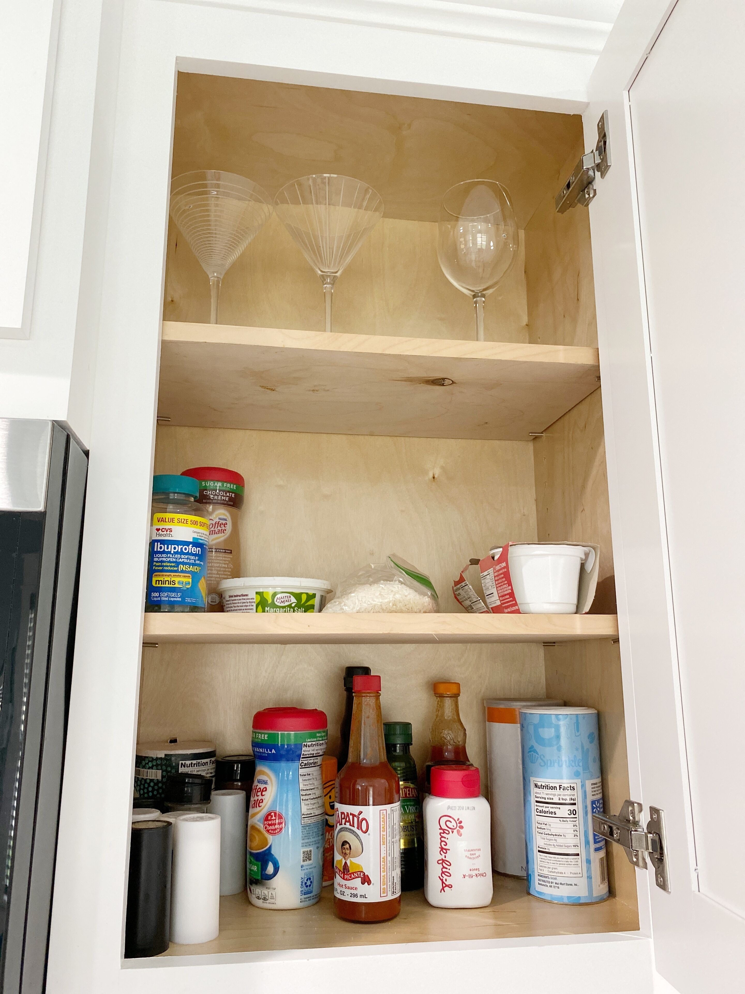 A kitchen cabinet with shelves containing various food items, a coffee maker, and a microwave.