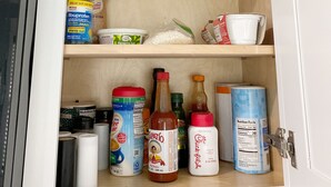 Un armario de cocina con estantes que contienen diversos alimentos, una cafetera y un microondas.