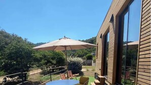 A patio with a table and chairs, a large umbrella, and a wooden bench area.