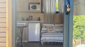 A cozy room with a bed, a small kitchenette, and a dining area.